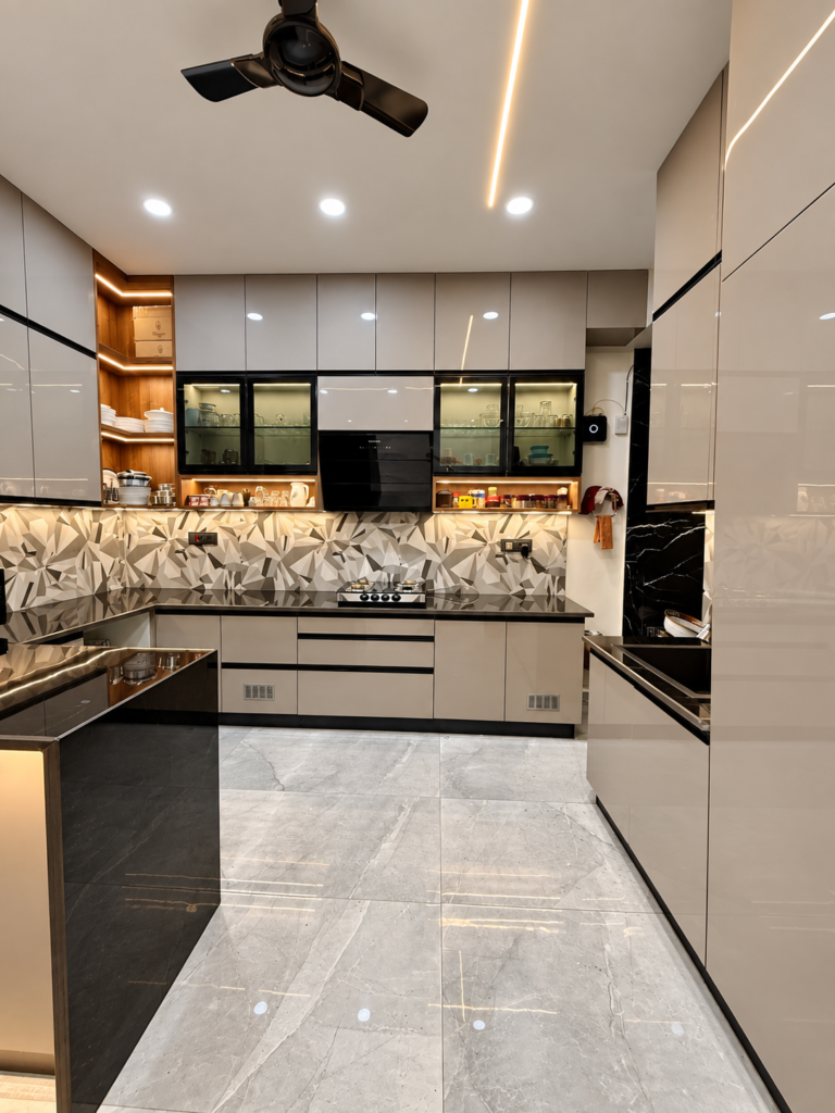 Wide view of modular kitchen with glossy light cabinets, black countertop and geometric backsplash, Lucknow